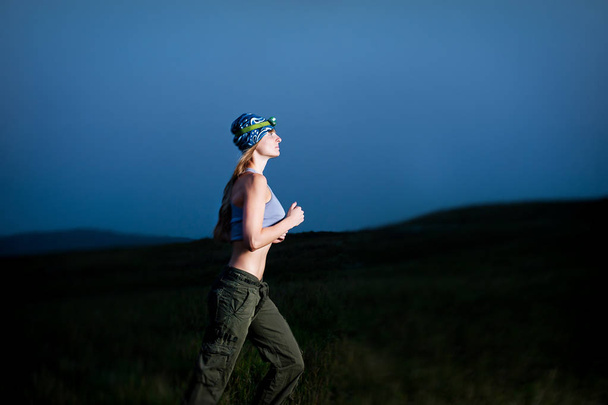 Mladá žena běžící ve tmě se světlometem - Fotografie, Obrázek