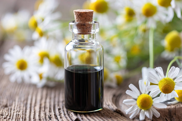 Butelka z ciemnoniebieskim olejkiem z rumianku i kwiatów - Zdjęcie, obraz