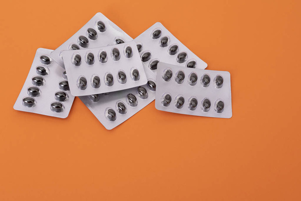 Set van pillen in een plastic blisterverpakking op oranje papier achtergrond - Foto, afbeelding