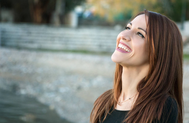 Πορτρέτο μιας γυναίκας γελώντας σε εξωτερικούς χώρους, κοιτάζοντας πάνω. - Φωτογραφία, εικόνα