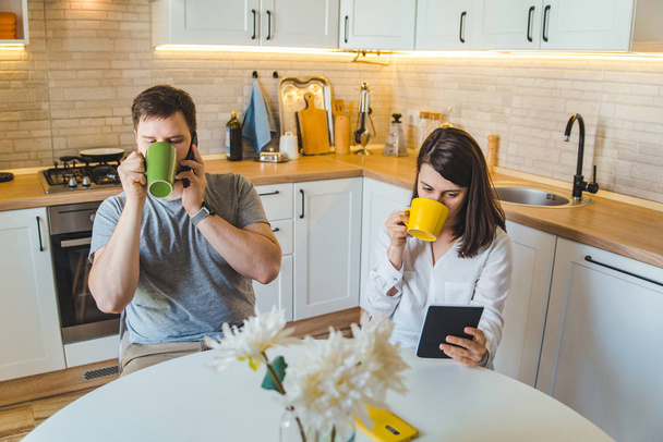 пара, сидящая на кухне по утрам, пьет чай, читая новости
 - Фото, изображение