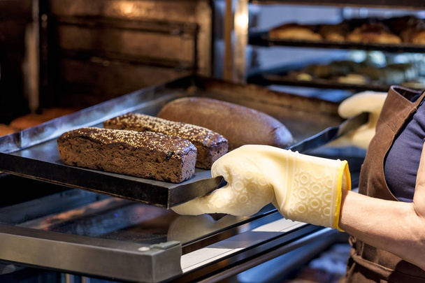padeiro segurando uma bandeja com pão fresco tirando-a do forno
. - Foto, Imagem