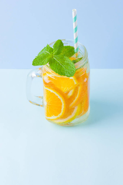 Infused water with fruits on blue background. Mug delicious refreshing drink of mix fruits with mint on blue background. Iced summer drink in mason jar. Minimalism - Zdjęcie, obraz