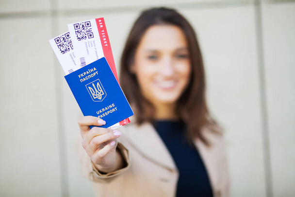 Путешествие. Женщина с двумя билетами в заграничном паспорте рядом с аэропортом
 - Фото, изображение