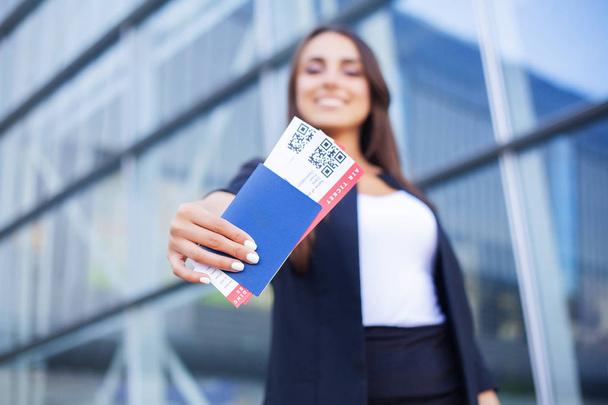 Ταξίδια. Γυναίκα που κρατά δύο αεροπορικά εισιτήρια στο εξωτερικό διαβατήριο κοντά στο αεροδρόμιο - Φωτογραφία, εικόνα