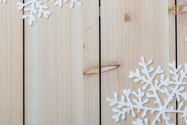 weiße künstliche Schneeflocken auf einem hellen Holztisch. Weihnachten und Neujahr Dekoration Hintergrund und Kopierraum für Text. Nahaufnahme - Foto, Bild
