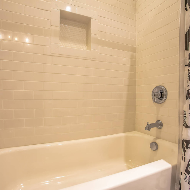 Neliön runko Kylpyamme ja suihku kylpyhuoneessa kiiltävällä valkoisella seinällä
 - Valokuva, kuva