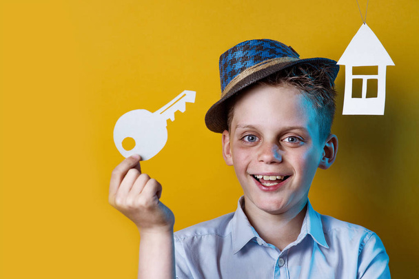 a cheerful boy with a cardboard house and a key on a bright colored background - Foto, Imagen