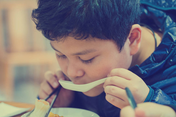Poika syö kiinalaista ruokaa.
. - Valokuva, kuva