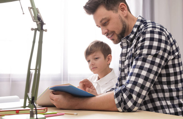 Dad helping his son with school assignment at home - Foto, Imagen