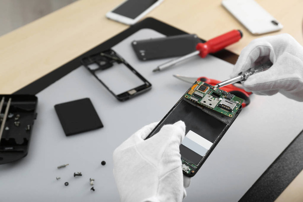 Technician repairing broken smartphone at table, closeup - Photo, Image