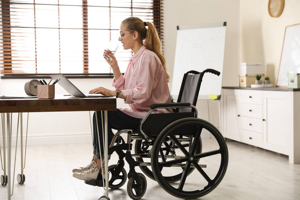 Donna in sedia a rotelle acqua potabile sul posto di lavoro
 - Foto, immagini