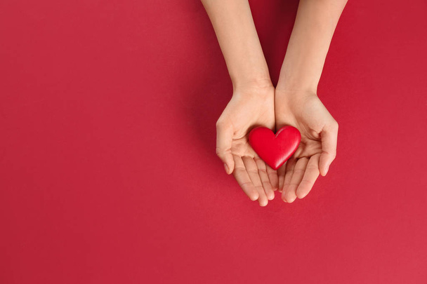 Woman holding decorative heart on color background, top view. Space for text - 写真・画像