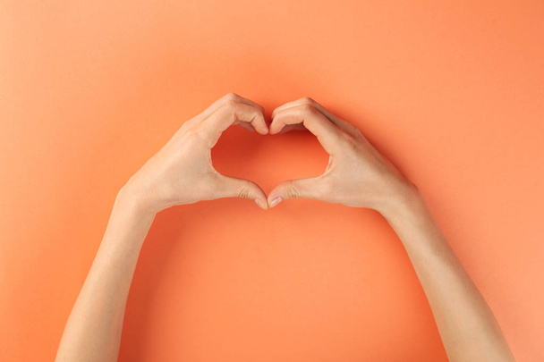 Woman making heart with her hands on color background, top view - Φωτογραφία, εικόνα