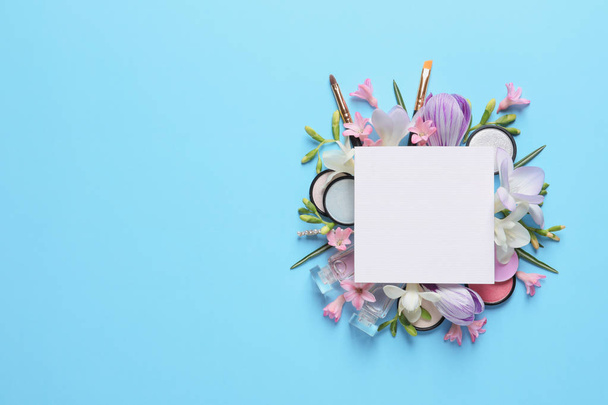 Makeup products, spring flowers and blank card on color background, flat lay. Space for text - Photo, Image