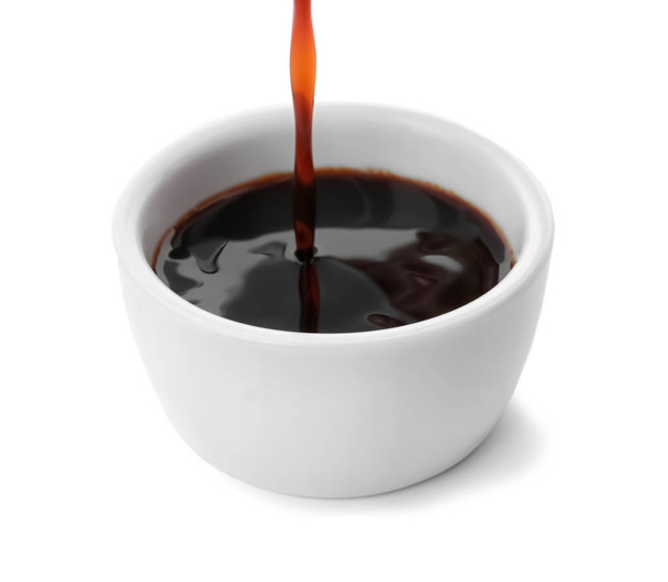 Pouring tasty soy sauce into bowl isolated on white - Photo, Image