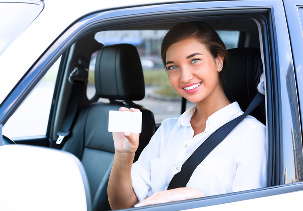 девушка в машине, показывающая пустую белую карточку для вашего сообщения
 - Фото, изображение