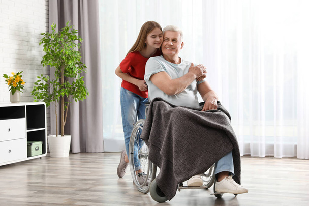 Tiener meisje met grootvader in rolstoel thuis - Foto, afbeelding