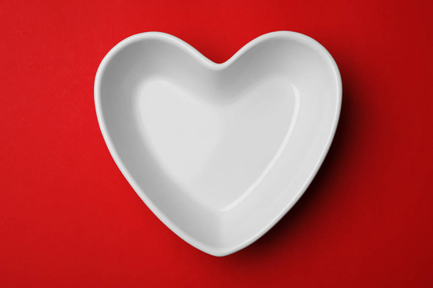 Heart shaped plate on color background, top view - Foto, Bild