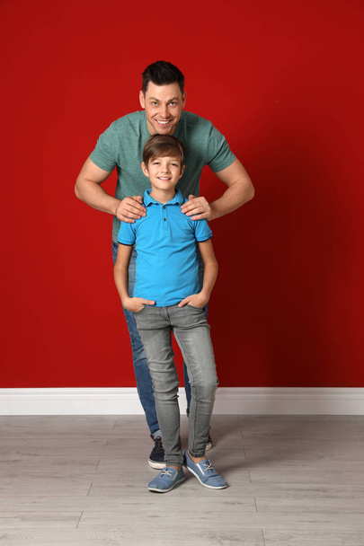 Portrait of dad and his son near color wall - Фото, зображення