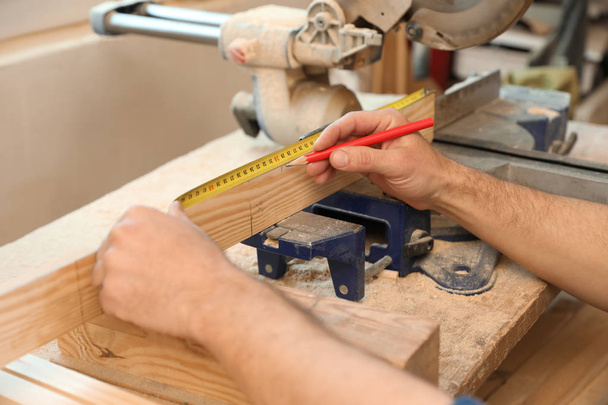 Working man measuring timber strip in carpentry shop, closeup - Photo, Image