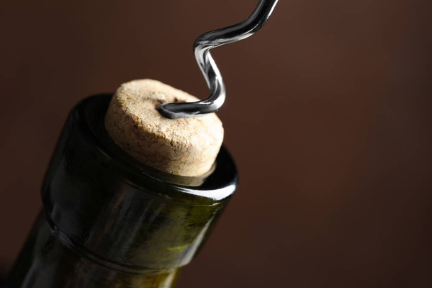 Opening wine bottle with corkscrew on color background, closeup. Space for text - Photo, Image