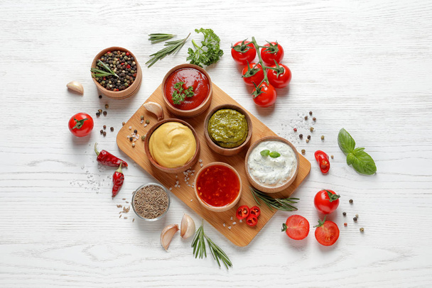 Flat lay composition with different sauces and ingredients on white wooden background - Foto, Bild