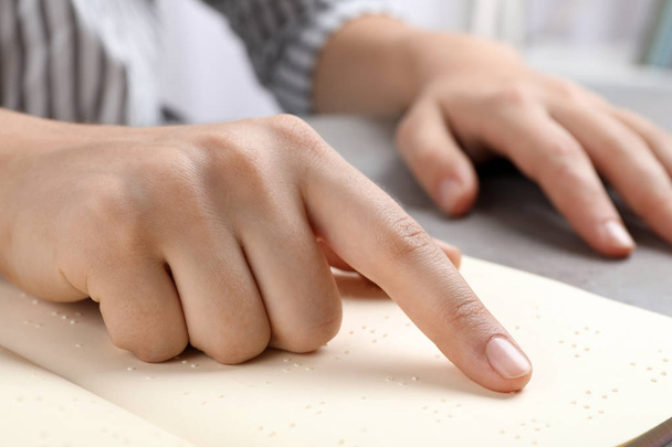 Blind person reading book written in Braille at table, closeup - Foto, imagen