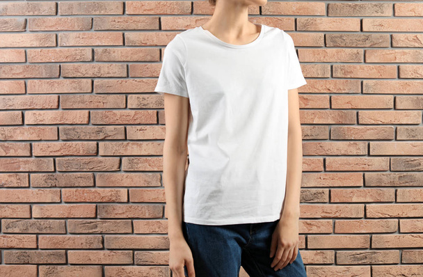 Woman in white t-shirt near brick wall. Mock up for design - Photo, image