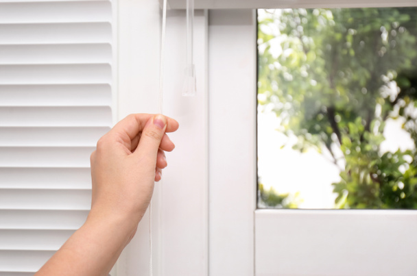 Woman opening white horizontal window blinds, closeup - Foto, Imagen