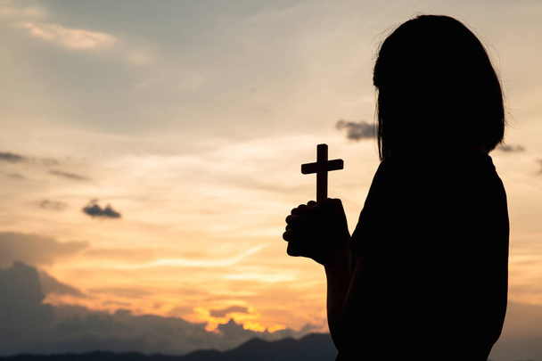 Religious concepts. Silhouette of a girl holding a crucifix to G - Photo, Image