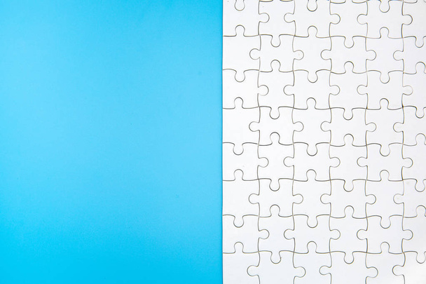 White jigsaw puzzle on blue background, Copy space. - Foto, Imagen