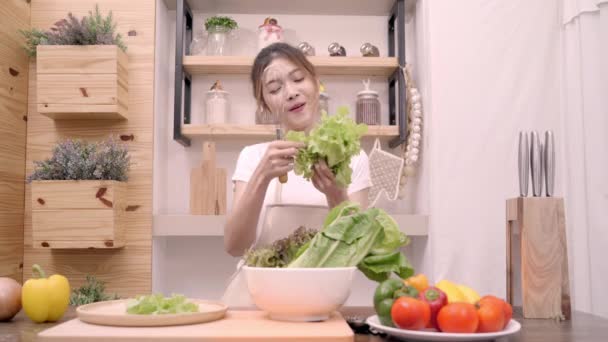 Blogger asiática haciendo ensalada en la cocina, Joven mujer sintiéndose feliz bailando y cantando una canción cocinando en casa. Estilo de vida influencer mujeres concepto saludable
. - Imágenes, Vídeo