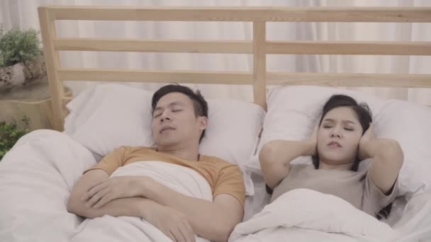 Asyalı çift eşi yatak odasında uyku zaman Snore kocası rahatsız, çift evde kadın uykusuzluk yatakta yatan ve uyuyamıyorum. Çift evde uyku kavramı. - Video, Çekim