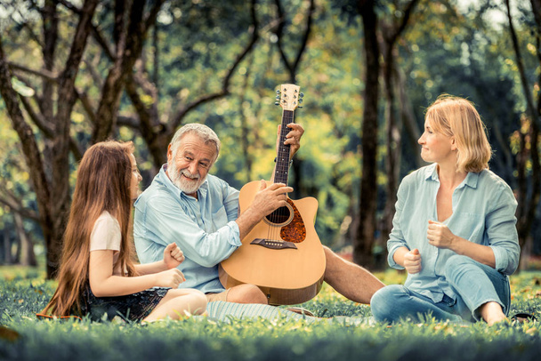 Happy family play guitar and sing together in park - Фото, зображення