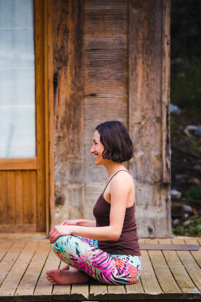 Жінка практикує йогу на ганку старого дерев'яного будинку
. - Фото, зображення