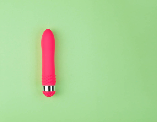 Beautiful evenly lit pink dildo on a plain green background with copy space. - 写真・画像