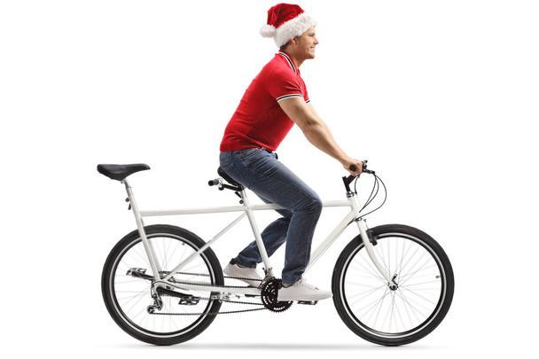 Young man wearing a santa claus hat and riding a tandem bicycle - Fotoğraf, Görsel