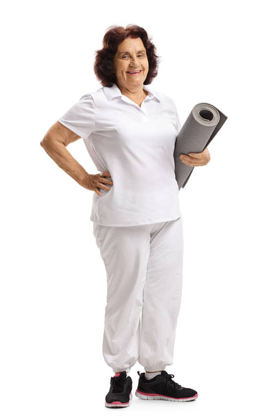 Elderly woman standing and holding an exercise mat - Foto, afbeelding