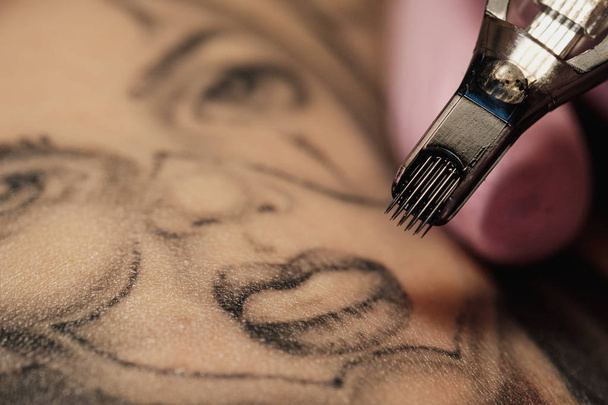 Close-up of a tattoo needle. The process of the tattoo master. Pink womens protective gloves. - Foto, Imagem