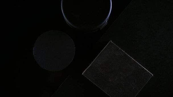 Тёмные предметы, выложенные в композиции на черном столе
 - Фото, изображение