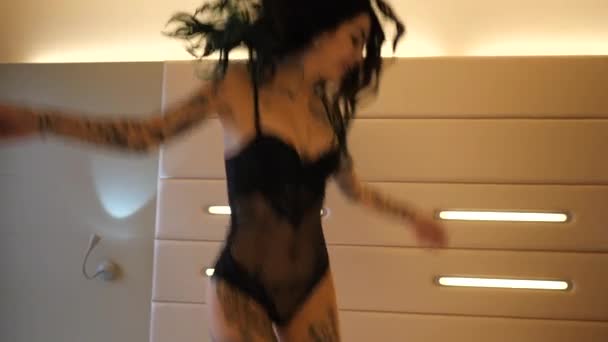 Tattooed young woman jumping in hotel room  - Footage, Video
