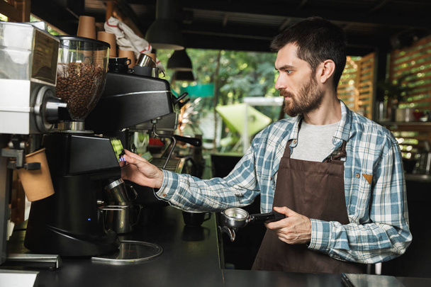 Portrait of serious barista man making coffee while working in s - Foto, Imagem