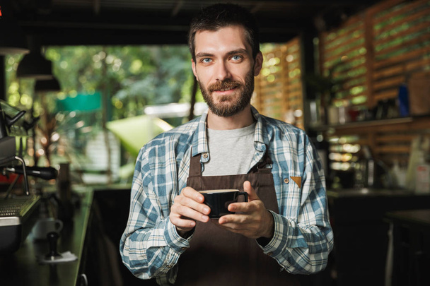 Image of kind barista man making coffee while working in cafe or - Фото, зображення