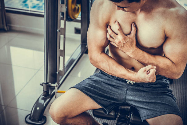 Hombre musculoso tocándose el pecho en el gimnasio
. - Foto, Imagen