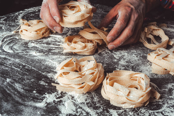 Homemade uncooked pasta on black background. Making fresh italia - Photo, Image