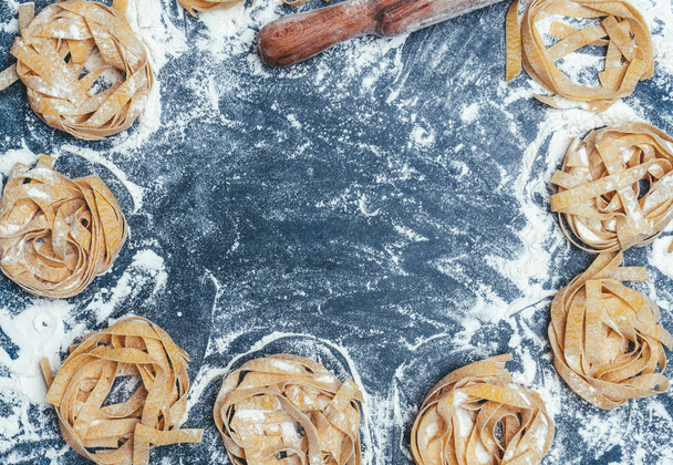 Homemade uncooked pasta on black background. Making fresh italia - Foto, Imagen