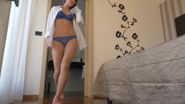Sensual young blonde woman portrait wearing lingerie walking to the bed in hotel room. - Filmmaterial, Video