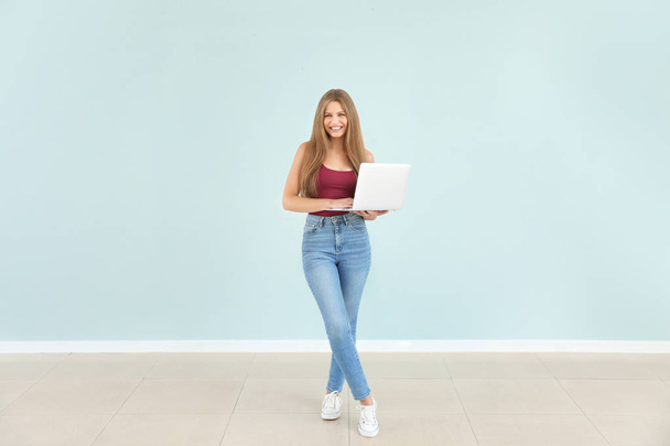 Piękna młoda kobieta z laptopem przed kolorową ścianą - Zdjęcie, obraz