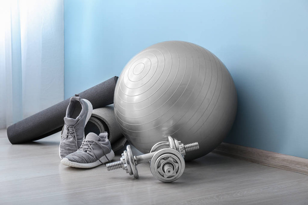 Set Sportgeräte mit Fitnessball und Schuhen in der Nähe der Farbwand - Foto, Bild